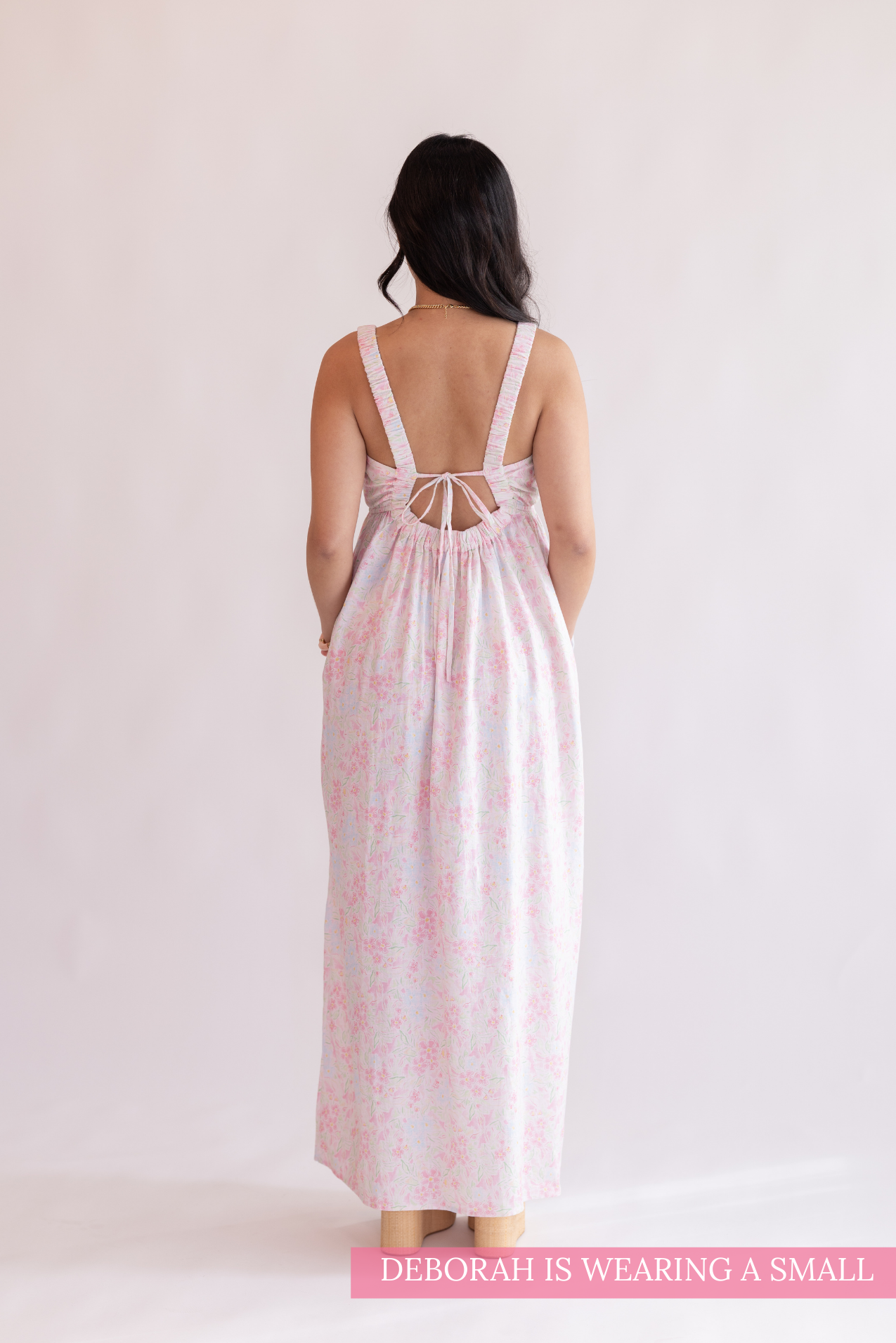 Woman wearing a pink floral dress with a white background