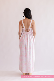 Woman wearing a pink floral dress with a white background