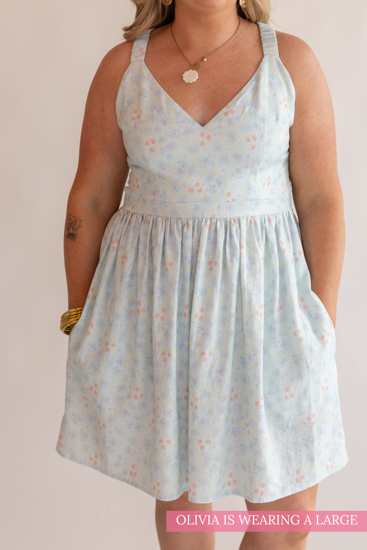 Woman wearing a light blue floral dress against a plain background