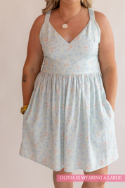 Woman wearing a light blue floral dress against a plain background