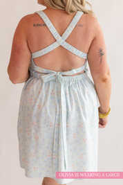 Light blue dress with floral pattern worn by a person on a plain background