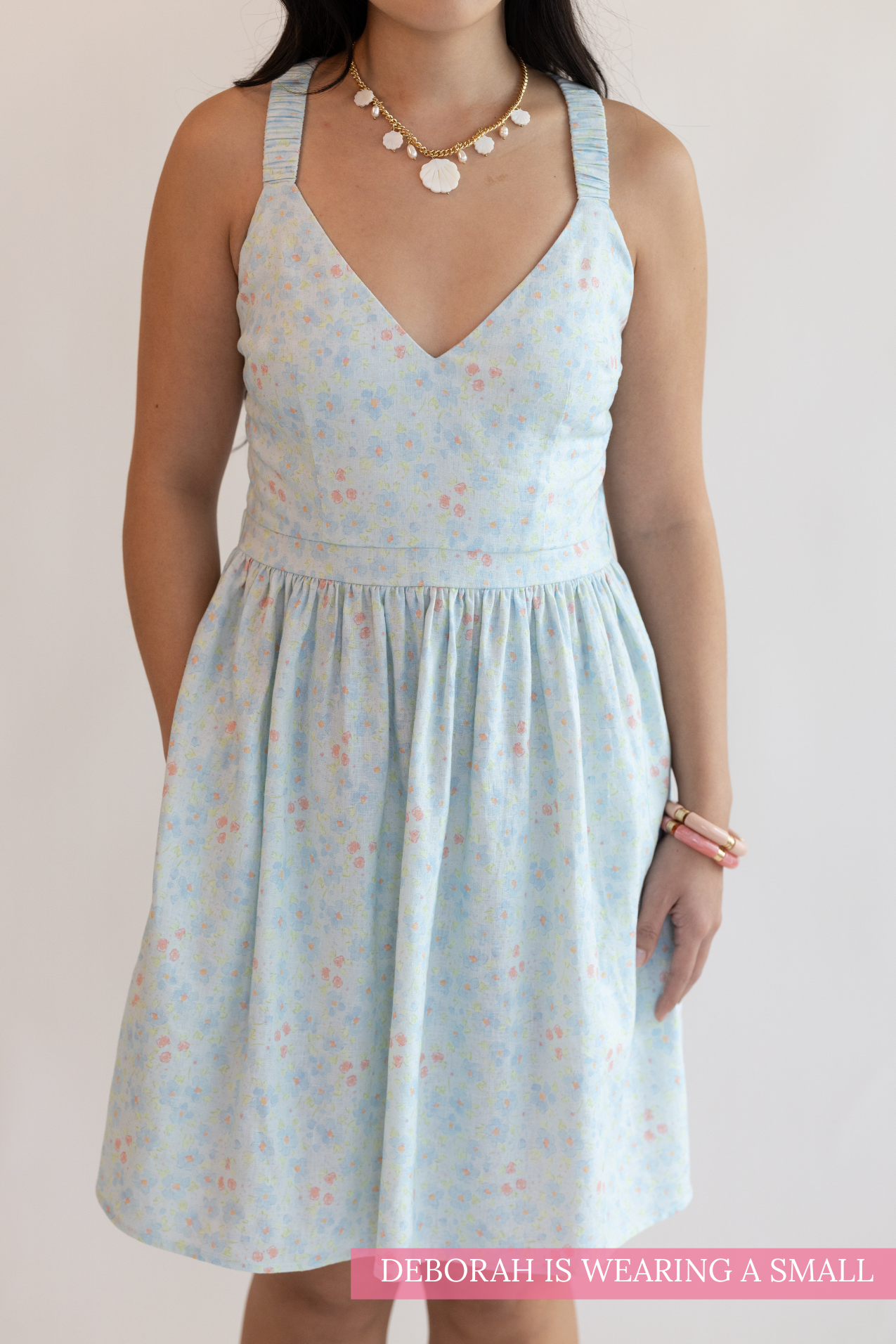 Woman wearing a light blue floral dress against a plain background