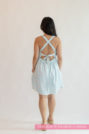Woman wearing a light blue dress with an open back on a plain background