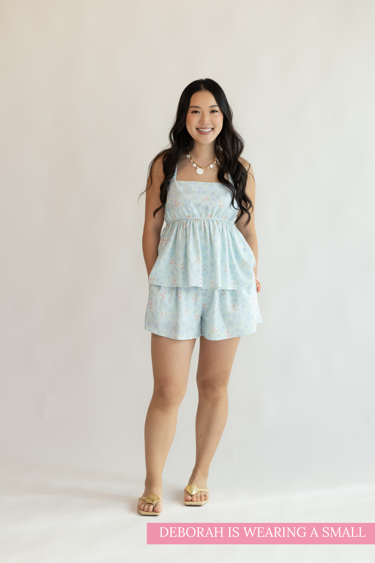 Woman wearing a light blue romper against a plain background