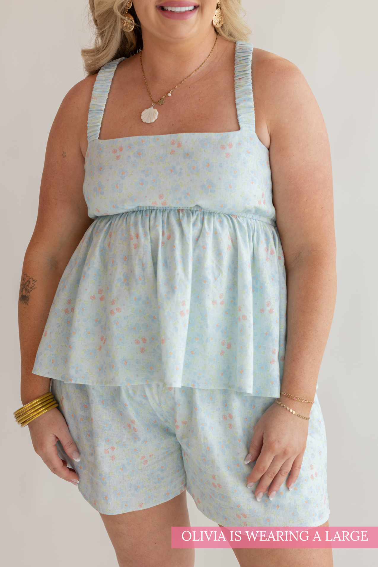 Woman wearing a light blue floral dress and shorts on a plain background