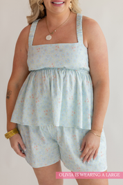 Woman wearing a light blue floral dress and shorts on a plain background