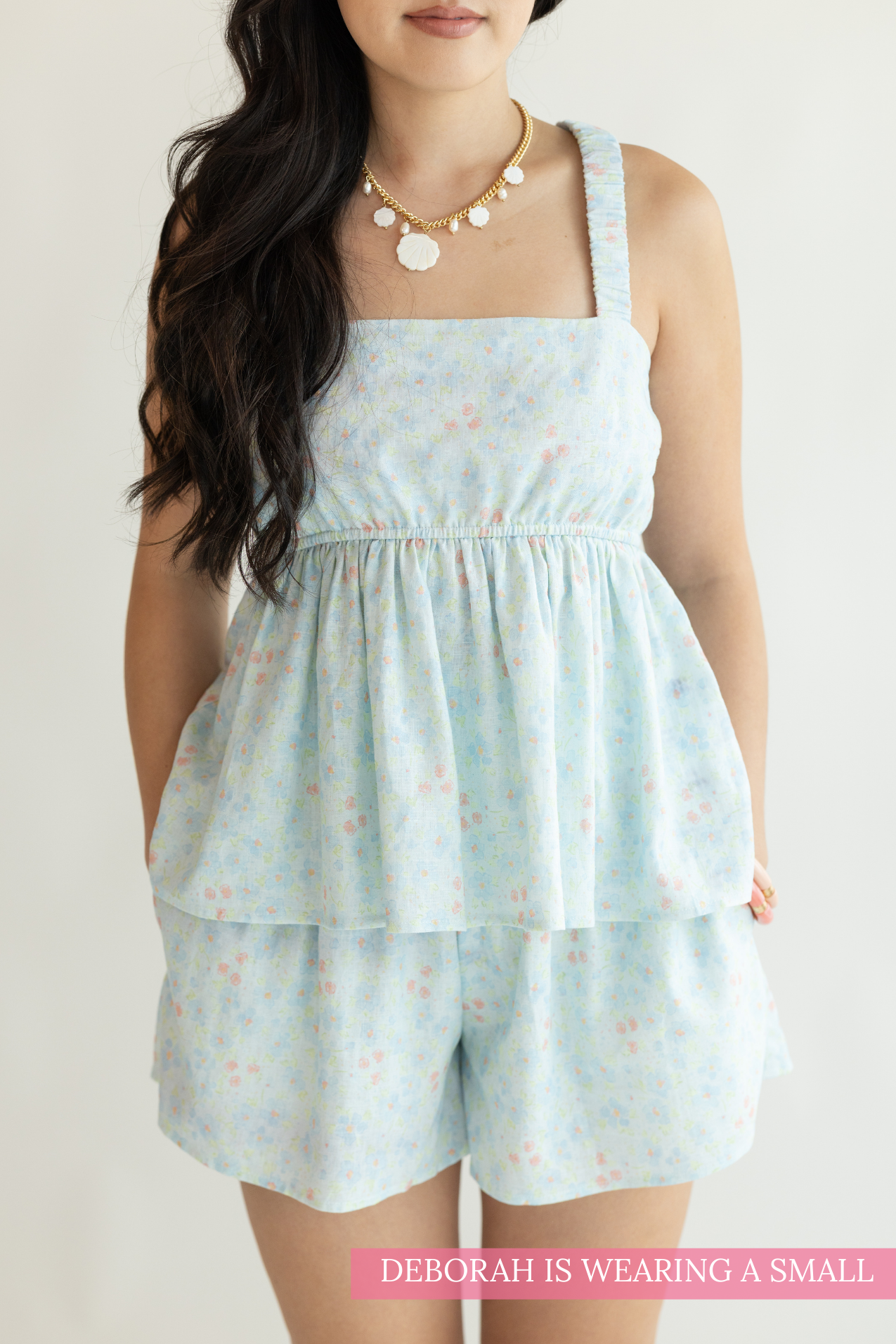 Woman wearing a light blue floral dress and shorts set on a white background