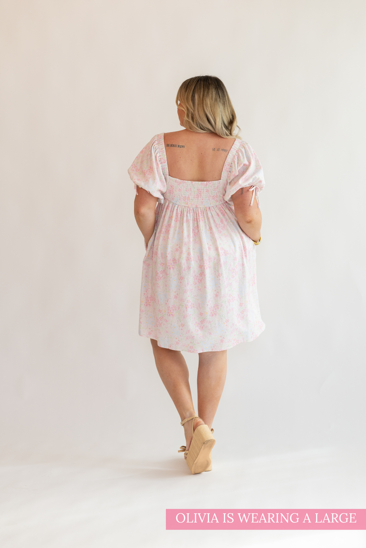 Woman wearing a light pink dress with floral patterns on a white background