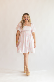 Woman wearing a light pink dress with a plain background
