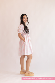 Woman wearing a pink checkered dress against a plain background