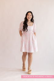 Woman wearing a pink dress with a plain background