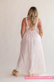 Woman wearing a light pink floral dress with a white background
