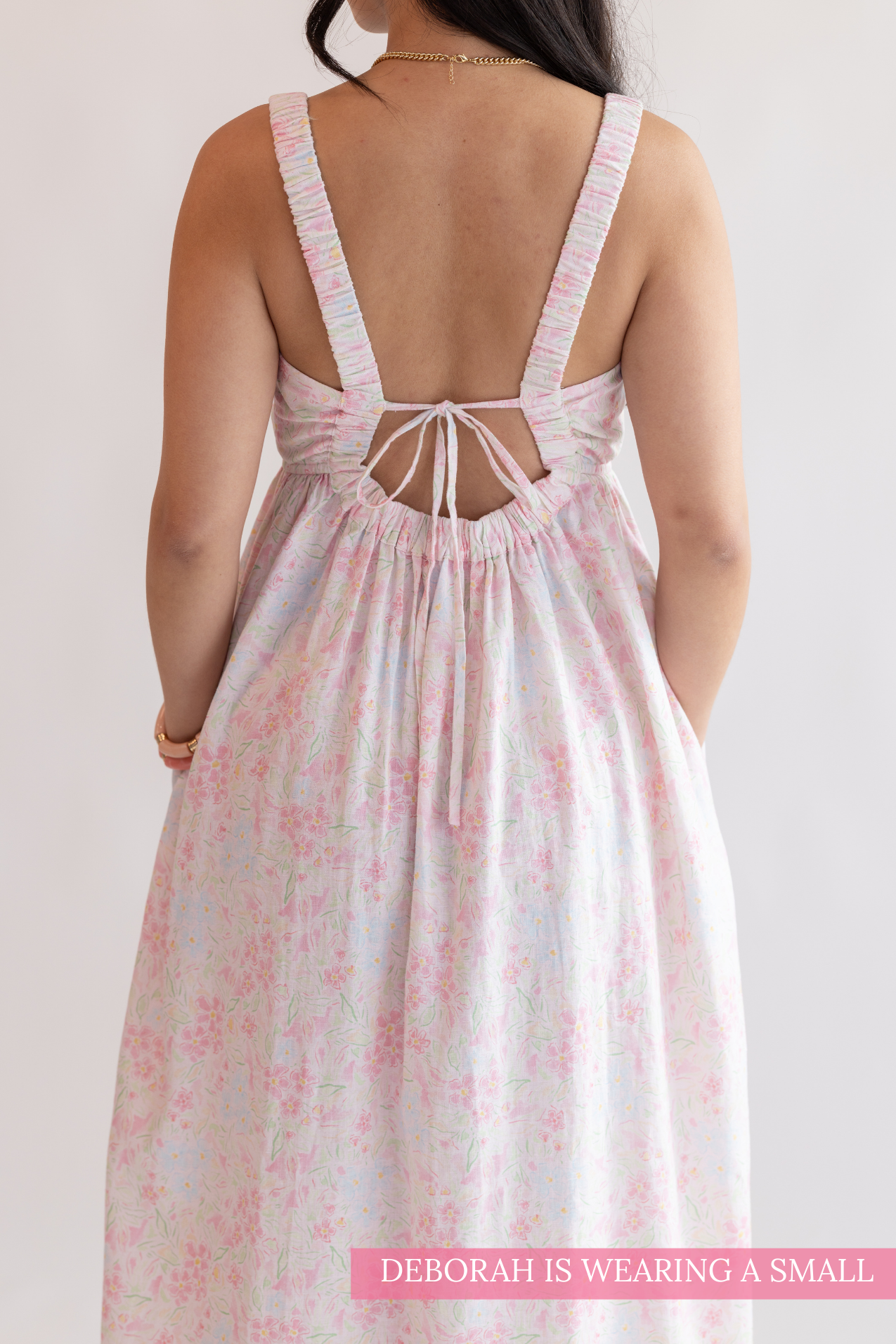 Woman wearing a floral dress with an open back on a plain background