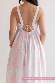 Woman wearing a floral dress with an open back on a plain background