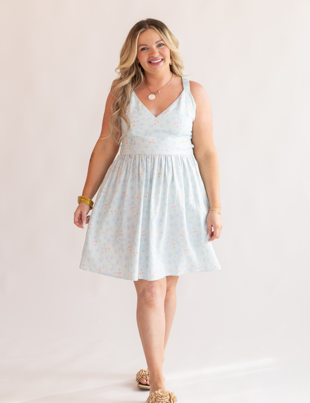 Woman wearing a light blue sleeveless dress against a plain background